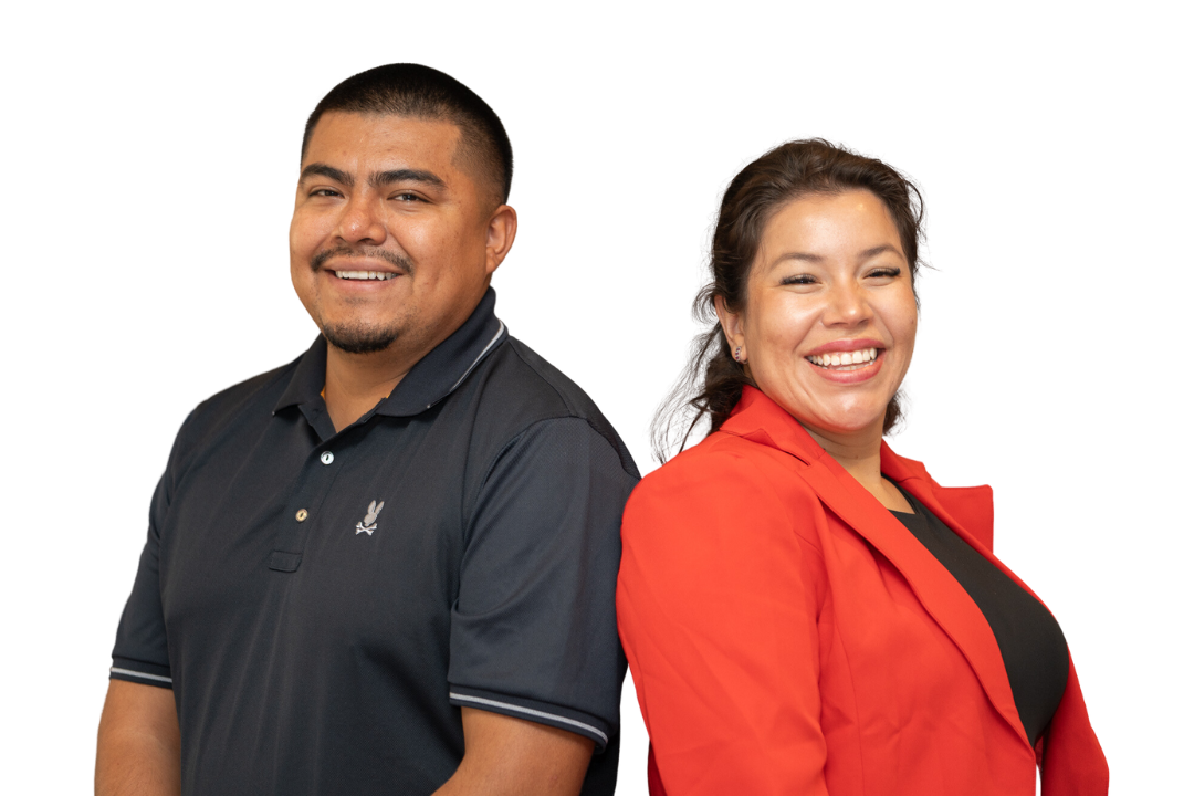 Smiling employees pose back to back in front of a white background
