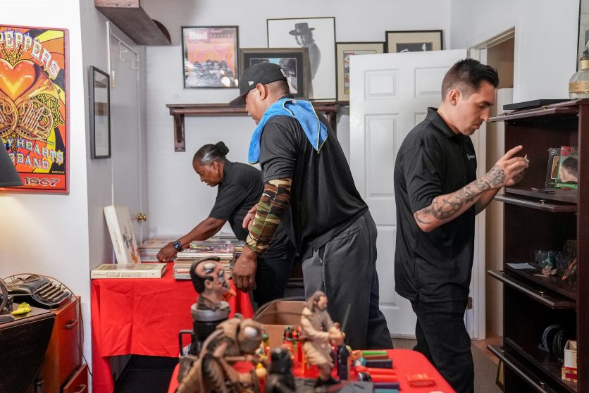 Three estate downsizing services employees organize collectibles in a room.